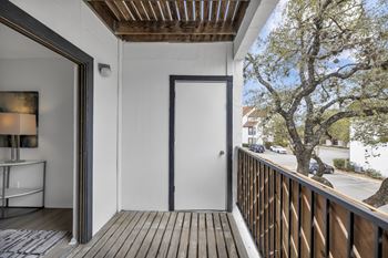 A balcony with a wooden floor and a white door.